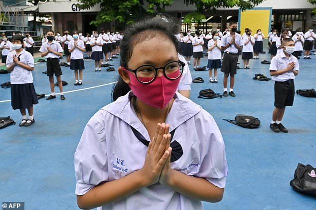 Students, socially distanced, attend a flag-raising ceremony at a secondary school in Bangkok